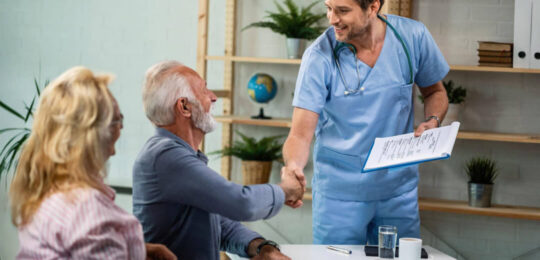 A healthcare provider greets an older patient with a handshake during a consultation, illustrating trust, communication, and choosing the right skilled nursing care.